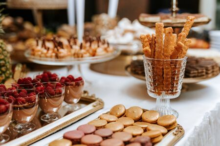 Wedding candybar with desserts, creamy and colorful pastries, delicious cookies, ananas, macarons, muffinsの写真素材