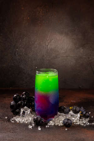 Delicious icy cocktail with fruits on dark grounge background. Healthy colorfull fruit shakes with ice on textured table.の写真素材