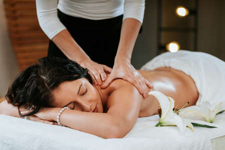 Masseur doing massage on beautiful young woman body in the spa salon. Professional masseur and clien concept.の写真素材