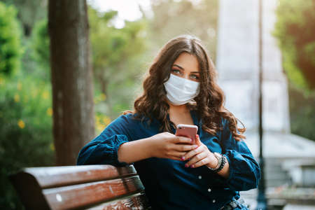 Corona virus lifestyle concept of a young women in city street who walks with surgical or protecting mask during pandemic.の写真素材