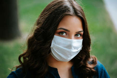 Corona virus lifestyle concept of a young women in city street who walks with surgical or protecting mask during pandemic.の写真素材