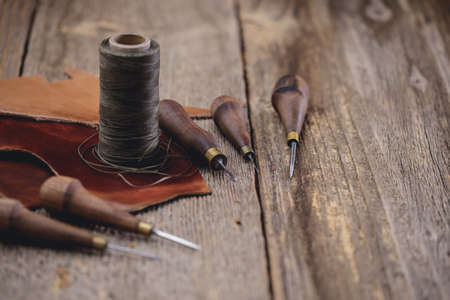 Leather craft tools on old wood table. Leather craft workshop.