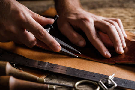 Leather craft tools on the old wood table in a shed. Leather craftsman workspace. Grounge dark wood texture background.の写真素材