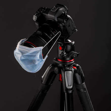 Digital mirrorless camera on massive tripod in studio with dark gray background. Professional...
