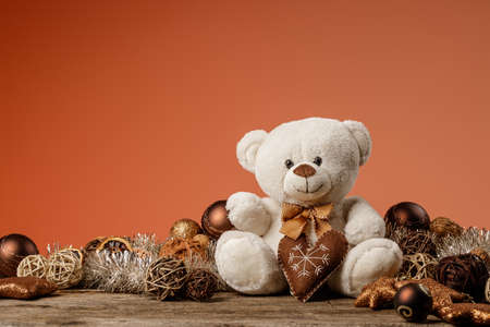 White or light brown adorable teddy bear with christmas decorations and gifts. Holiday concept with toy plush bear and christmass gifts on the wood table.の写真素材