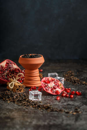 Hookah ceramic head fulled with aromated molose, pomegranade, blueberry and ice cubes on the grunge...