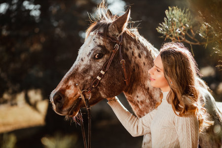 Beautiful young girl posing with her horse in the nature. Sunny autumn day.の写真素材