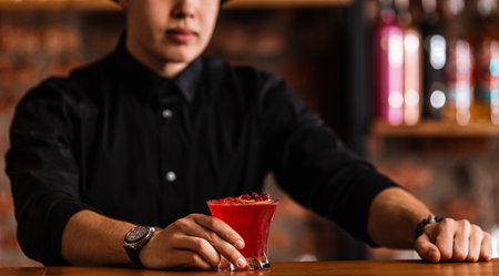 Deliciouse cranberry cocktail with ice cubes. Expert barman makes cranberry cocktail at the bar. Red alcoholic drink.の写真素材