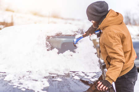 Man clear snow from car with cleaning tool