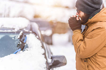 Man clear snow from car with cleaning toolの写真素材