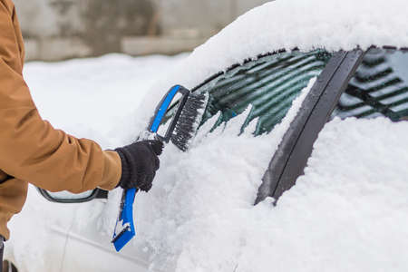 Man clear snow from car with cleaning tool