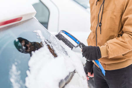 Man clear snow from car with cleaning toolの写真素材