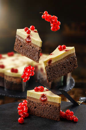Confectionery concept with flying cakes with red currant, chocolate mouss and cheese cream on the top. Levitated fresh baked healthy dessert.の写真素材