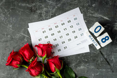 International Womans day concept with calendar pages of year 2021 of march and red roses on gray...