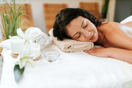 Beautiful young woman in the massage salon with brown curly hair and healthy skin. Masseur and patient concept.の写真素材