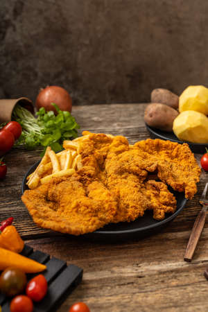 Crispy pork fried in a black plate on a rustic wooden tableの写真素材