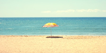 White sandy beach and blue sky with a yellow umbrellaの写真素材