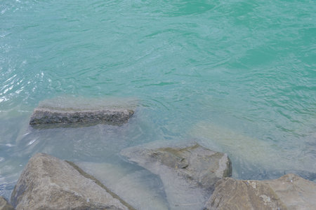 The surface of the water in the lake with a stone in the foreground Beautiful landscape in an evening mood by the water in the sunshine.の写真素材