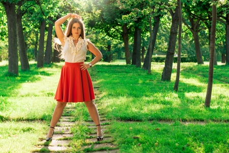 Portrait of young girl in a red skirt in parkの写真素材