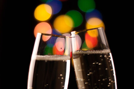 two glasses of champagne toasting against bokeh lights backgroundの写真素材