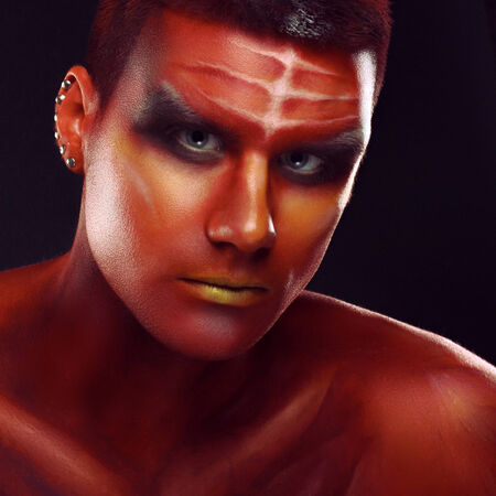 Portrait of a handsome young man in a red body painting