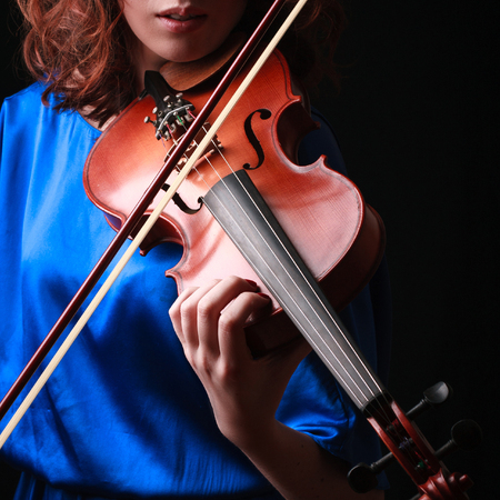 Violin with performer hands on dark background.の写真素材