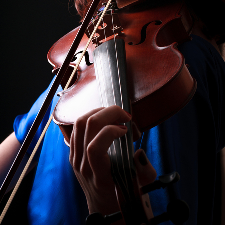 Violin with performer hands on dark background.の写真素材