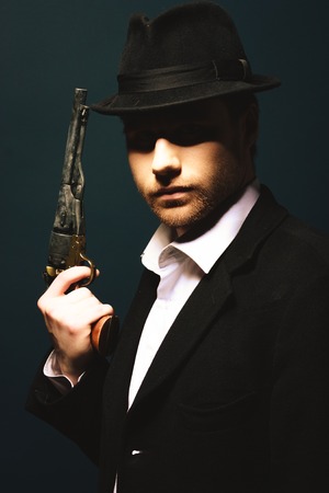 Photo of man shot with studio lighting, holding a handgunの写真素材