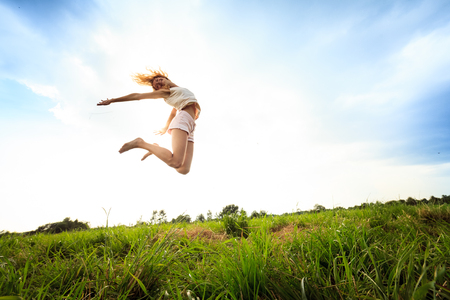 Jumping girl  at field in summer. outdoor shotの写真素材