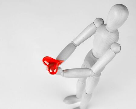 Classic wooden dummy holds red little heart for Valentine's Day.