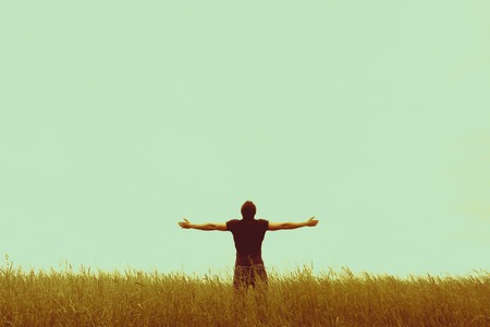 Silhouette of young man standing with hands open wideの写真素材