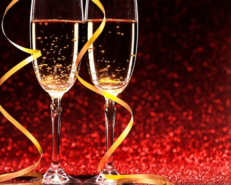 glasses of champagne with yellow holidays ribbons, on red backgroundの写真素材