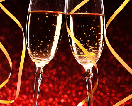 glasses of champagne with yellow holidays ribbons, on red backgroundの写真素材