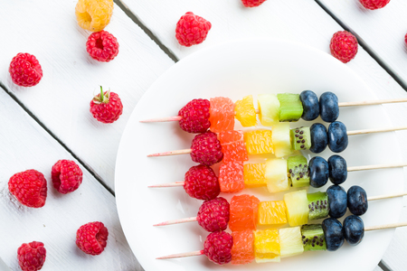Coloerd fruits and berries kebab on wooden tableの写真素材