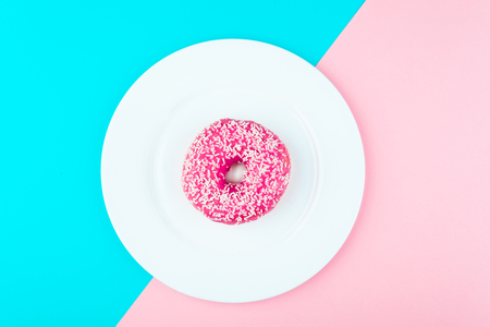 Minimalism, colour contrast on a blue and pink background, donut photo from above in flat styleの写真素材