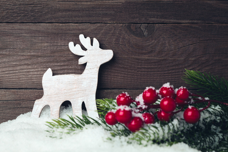 Christmas deer toy and tree on snow over wooden backgroundの写真素材