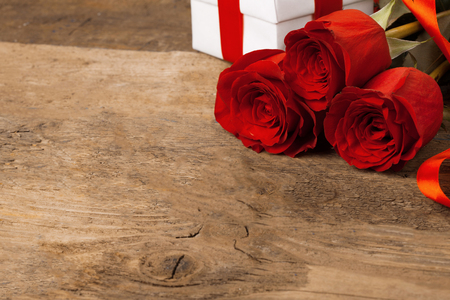 Three beautiful red roses lie on a wooden surface.の写真素材