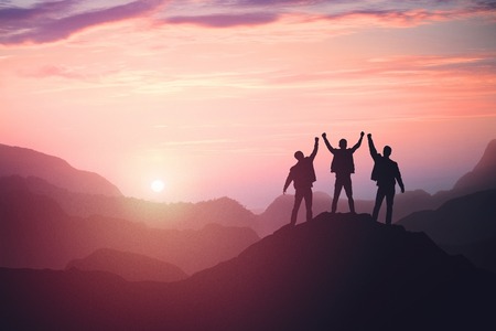 three guys celebrating victory on top of a mountainの写真素材