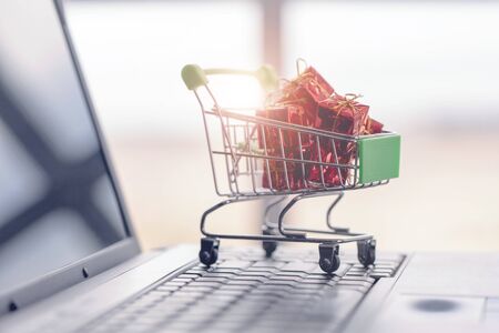 Gift boxes in a shopping cart on a laptop keyboard.の写真素材