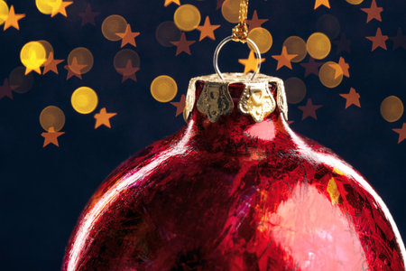 Red christmas ball with gold lights on dark blue background, close up