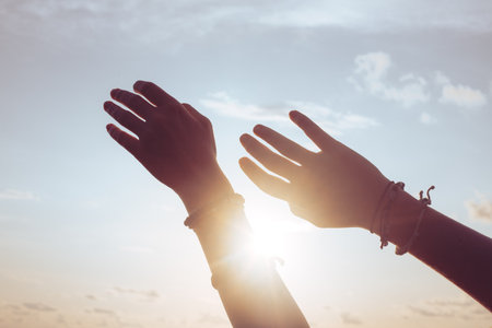 Woman hands against blue sky and sunの写真素材
