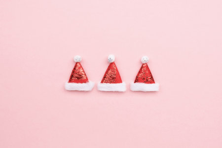 Santa Claus hats on a pink background, minimalistic christmas background with copy spaceの写真素材