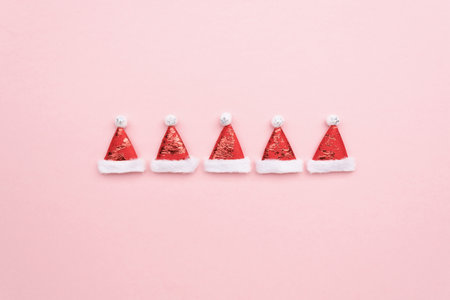 Santa Claus hats on a pink background, minimalistic christmas background with copy spaceの写真素材