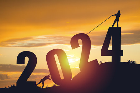 Silhouette of men pushing and pulling the year 2024 against a golden sunrise backgroundの写真素材