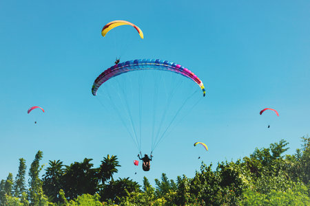 Paraglider in the blue sky. The sportsman flying on a paraglider.