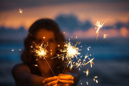 Happy young woman holding sparkler celebrating new years eve on the beach