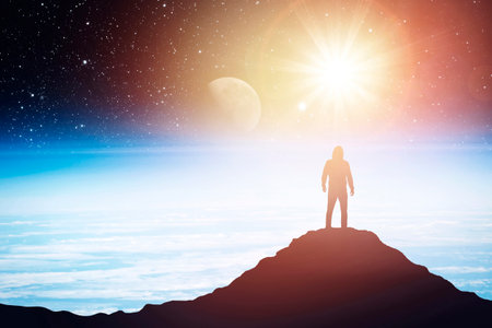 Silhouette of a man standing on the top of a mountain against the backdrop of the planet.の写真素材