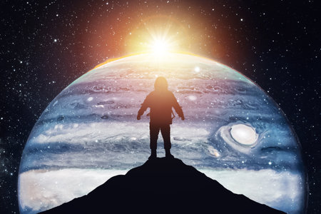 Silhouette of an astronaut on top of a mountain against the backdrop of the planet, the concept of conquering other worlds.の写真素材