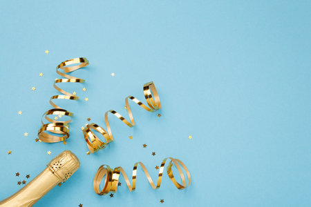 A beautiful bottle of champagne accompanied by bright gold streamers elegantly displayed on a vibrant blue background, creating a striking visual appealの写真素材