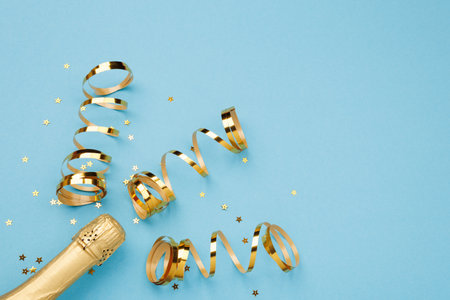 Champagne bottle with confetti stars on color background, space for text, flat lay.の写真素材